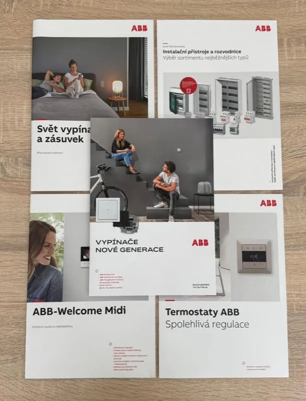 Katalogy ABB rozložené na stole — vypínače, instalační přístroje, termostaty a videotelefony